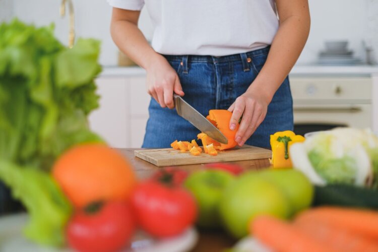 persona cocinando o preparando una comida con vegetales variados