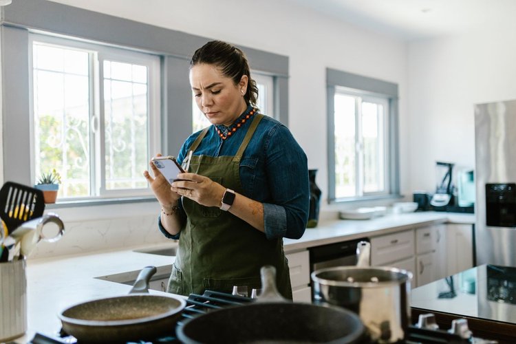 De aficionado a formulador: guía para crear tus propios productos capilares naturales con éxito Mujer concentrada consultando una receta en el móvil en la cocina para hacer cosmética casera